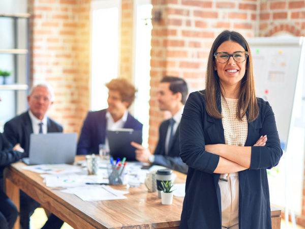 Group of business workers smiling happy and confident working together in a meeting. One of them, standing with smile on face looking at camera at the office.